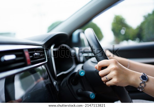 Happy Asian woman driving the electric vehicle -\
EV car smiling and showing her thumb up to the camera, happy and\
safety driving concept. Woman driving modern EV car and smiles to\
camera.