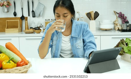 Happy asian woman eating healthy food drinks watch online movie. Women enjoy video call web conference live streaming home kitchen use digital tablet. Female use smart phone online call social media - Powered by Shutterstock