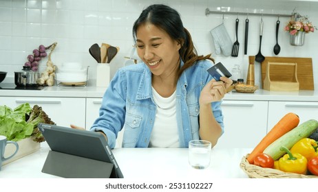 Happy asian woman eating healthy food drinks watch online movie. Women enjoy video call web conference live streaming home kitchen use digital tablet. Female use smart phone online call social media - Powered by Shutterstock