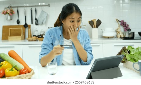 Happy asian woman eating healthy food drinks watch online movie. Women enjoy video call web conference live streaming home kitchen use digital tablet. Female use smart phone online call social media - Powered by Shutterstock