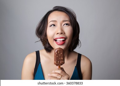 Happy Asian Woman Eating Ice Cream, Looking Up To Copy Space.