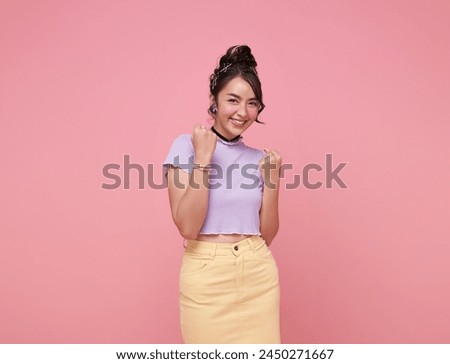 Happy Asian woman excited overjoyed standing with raised fists and shouting yeah, I'm winner, rejoicing victory, success isolated on pink background.
