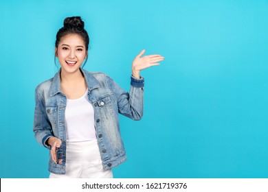 Happy asian woman feeling happiness and standing hold smartphone other hand open on blue background. Cute asia girl smiling wearing casual jeans shirt and connect internet shopping online and present