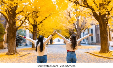 Happy Asian woman friends enjoy and fun outdoor lifestyle travel and walking at park with looking beautiful yellow ginkgo tree leaves falling down in autumn in Tokyo city, Japan on holiday vacation. - Powered by Shutterstock