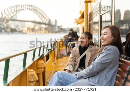 Happy Asian woman friends sitting on ferry boat crossing Sydney harbour in Australia. Attractive girl enjoy and fun urban outdoor lifestyle shopping and travel in the city on holiday vacation.