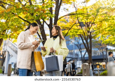 Happy Asian woman friends walking and shopping together at Shibuya district, Tokyo, Japan in autumn. Attractive girl enjoy and fun outdoor lifestyle walking and travel city street on holiday vacation. - Powered by Shutterstock