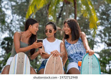 Happy Asian woman girl friends sit on the beach using smartphone for online shopping or social media together. Female friendship enjoy and having fun outdoor activity lifestyle in summer vacation. - Powered by Shutterstock