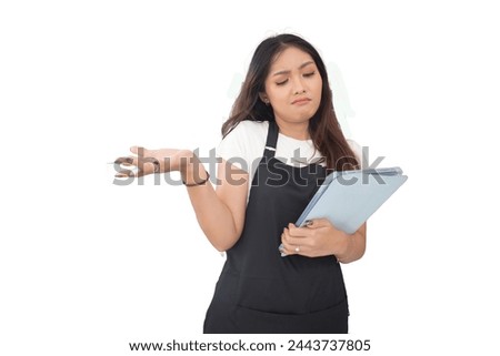 Happy Asian woman as groceries or modren market staff checking products and goods on the display shelf while holding tablet and wearing black apron isolated white background
