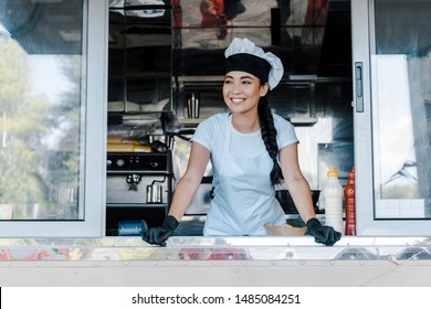 Happy Asian Woman In Hat And Chef Uniform Smiling In Food Truck 