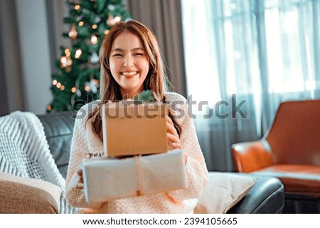 Happy asian woman holding many Christmas present boxes, celebration concept - Smiling female with many Christmas gift boxes in living room at home