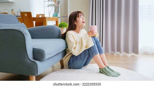 happy asian woman holding mug drink beverage feeling cozy and warm enjoying sitting in living room at home during winter - Powered by Shutterstock