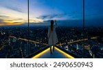 Happy Asian woman looking beautiful metropolis cityscape at skyscraper building rooftop at sunset. Attractive girl relax and enjoy outdoor lifestyle travel and shopping in the city on holiday vacation