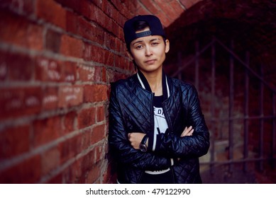 Happy asian woman near brick wall. Playing emotion. Close up androgynous portrait girl in black cap and coat. Dark concept. - Powered by Shutterstock