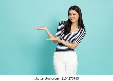 Happy Asian woman open hand palm with copy space for product isolated on green background - Powered by Shutterstock