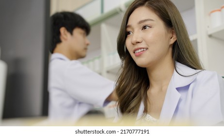 Happy Asian Woman Pharmacist In Drugstore Or Pharmacy Using Computer