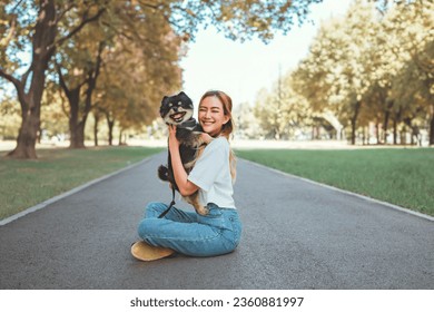 Happy asian woman playing with dog together in park outdoors, summer vacation. - Shutterstock ID 2360881997