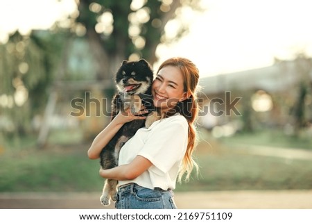 Happy asian woman playing with dog on the park in sunset light, summer vacation.