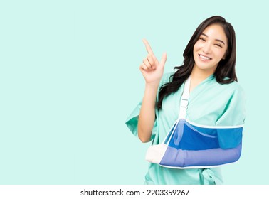 Happy Asian Woman Put On Soft Splint Due To A Broken Arm Point Up To Space Isolated On Green Background Patient Female Wearing Hospital Gown Patient Insurance Health Care And Personal Accident Concept