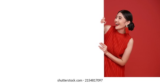 Happy Asian Woman In Red Casual Attire With Blank Announcement Banner In Red Background.