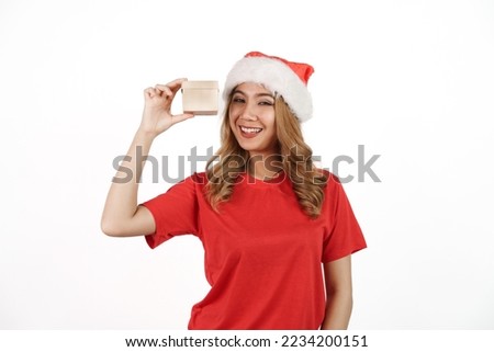 Happy asian woman in santa hat and red t-shirt isolated on white background. Holding small gift box