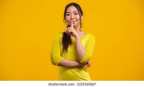 Happy Asian Woman Showing Hush Sign And Smiling Isolated On Yellow 