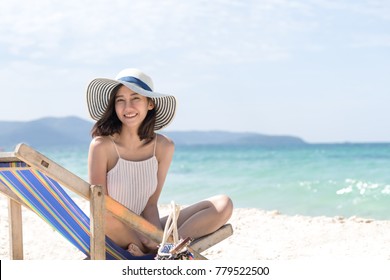 Happy Asian Woman Sitting At The Beach Have Copy Space On Right Handside. Relax And Travel Concept.