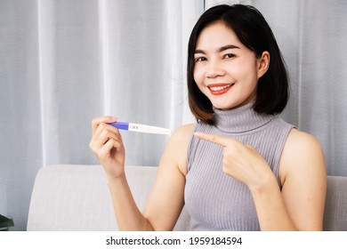 Happy Asian Woman Smiling Hand Holding At Pregnancy Test Showing Positive Result  