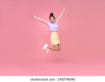 Happy Asian woman smiling and jumping while celebrating success isolated over pink background. - Shutterstock ID 1950798340