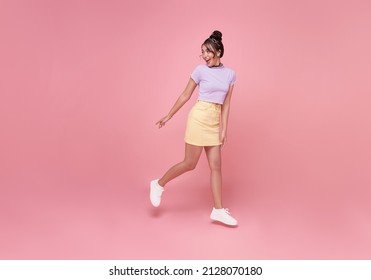 Happy Asian woman smiling and  Jumping like running while her looking back at pink copy space background.