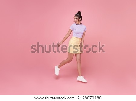 Happy Asian woman smiling and  Jumping like running while her looking back at pink copy space background.