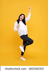 Happy Asian Woman Smiling And Standing With Hand Up Celebrating Gesture On Yellow Background.