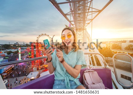 Happy asian woman smiling and taking selfie photo on a ferris wheel