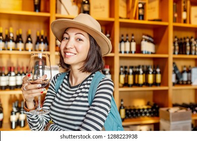 Happy Asian Woman Sniffing And Tasting Red Wine In A Glass In Winery Shop