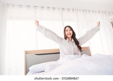 Happy Asian Woman Stretching Hands In Bed After Wake Up In The Morning, Concept Of A New Day And Joyful Weekend.