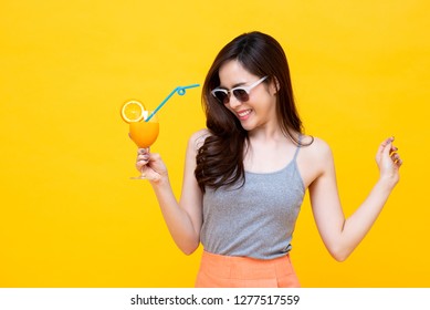 Happy Asian Woman In Summer Casual Clothes With A Glass Of Fresh Fruit Juice Drink Studio Shot Isolated On Colorful Yellow Backgroud