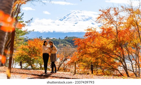 Happy Asian woman travel Japan on holiday vacation. Attractive girl friends using mobile phone taking selfie together while travel Mt.Fuji and looking beautiful red maple tree leaf falling in autumn - Shutterstock ID 2337439793