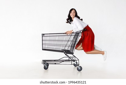 Happy Asian Woman With Trolley Shopping Cart In Sideview On White Isolated Background