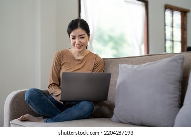 Happy Asian Woman Using Laptop In The Sofa With A Happy Face Standing And Smiling With A Confident Smile Showing Teeth