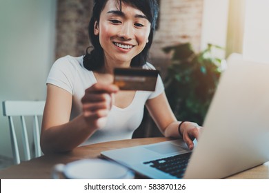 Happy Asian Woman Using Laptop And Creditcard For Online Shopping At Home.Blurred Background,flares Effect