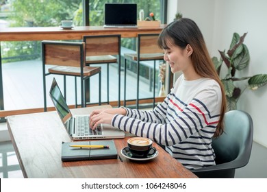 Happy Asian Woman Using On Laptop Computer While Working Near Window At Cafe Restaurant,Digital Co Working Space Lifestyle.influencer Blogger Review.working Outside Office