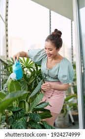 Happy Asian Woman Watering Plant On The Balcony.