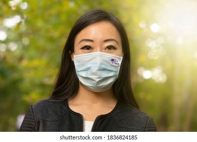 Happy Asian Woman Wearing Face Mask and I Voted Sticker - 2020 Presidential Election During Coronavirus Pandemic