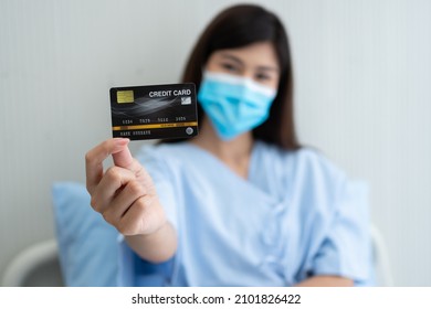 Happy Asian Woman Wearing A Medical Mask And Holding Mock Up Credit Card Insurance Card And Ok Sign In A Hospital Bed. Insurance Policy By Bank, Payment Medical Treatment Concept