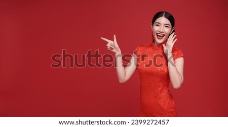 Happy Asian woman wearing red dress shouting announce and hands pointing finger to copy space isolated on red background.