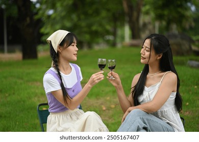 Happy asian women friends having fun outdoor and toasting with wine glasses at picnic. - Powered by Shutterstock