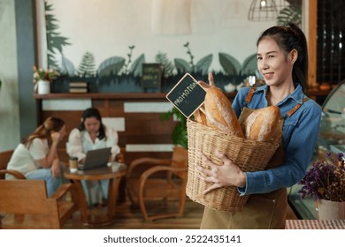 Happy Asian worker in a denim shirt showcases a selection of bread, hospitality at its best. happiness of opening a coffee shop in the morning small family business - Powered by Shutterstock