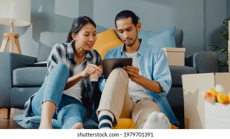 Happy asiatische junge attraktive Paar Mann und Frau nutzen Tablet-Online-Shopping Möbel schmücken Haus mit Karton-Paket Umzug in neues Haus. Junge verheiratete asiatische Heimkäufer Online-Konzept.
