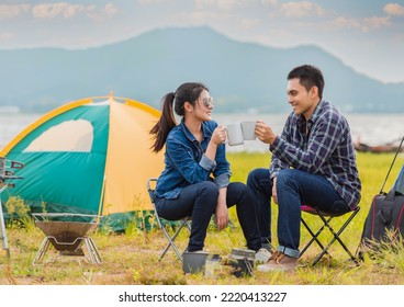 Happy Asian young couple sitting on picnic chair drinking tea and coffee while tent camp lakeside at parks outdoors on vacation holiday. Adventure lifestyle of man and woman with camping in nature. - Powered by Shutterstock