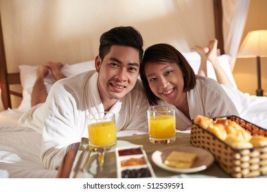 Happy Asian Young Couple Spending Honeymoon In Hotel