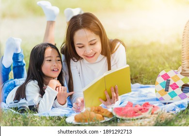 Happy Asian young family mother and child little girl having fun and enjoying outdoor laying on picnic blanket reading book at summer garden spring park, Family relaxation concept - Powered by Shutterstock